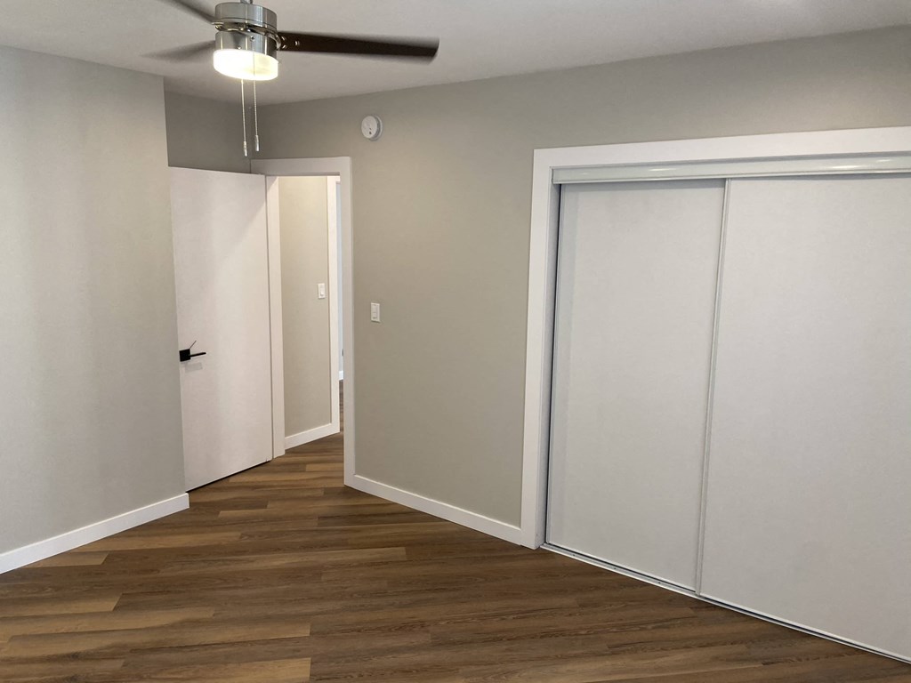 a room with two closets and a wood floor and a ceiling fan