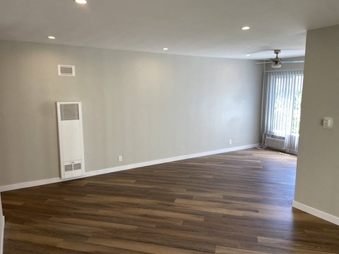 a renovated living room with wood floors and a window