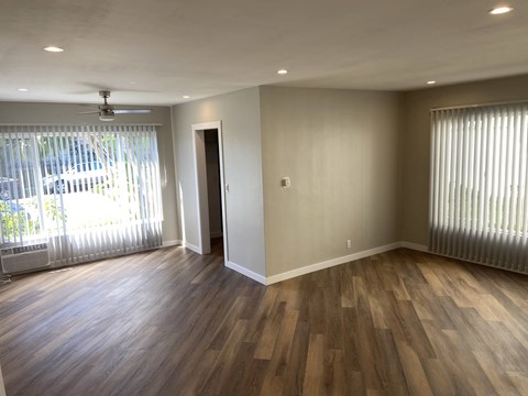 an empty living room with wooden floors and a window