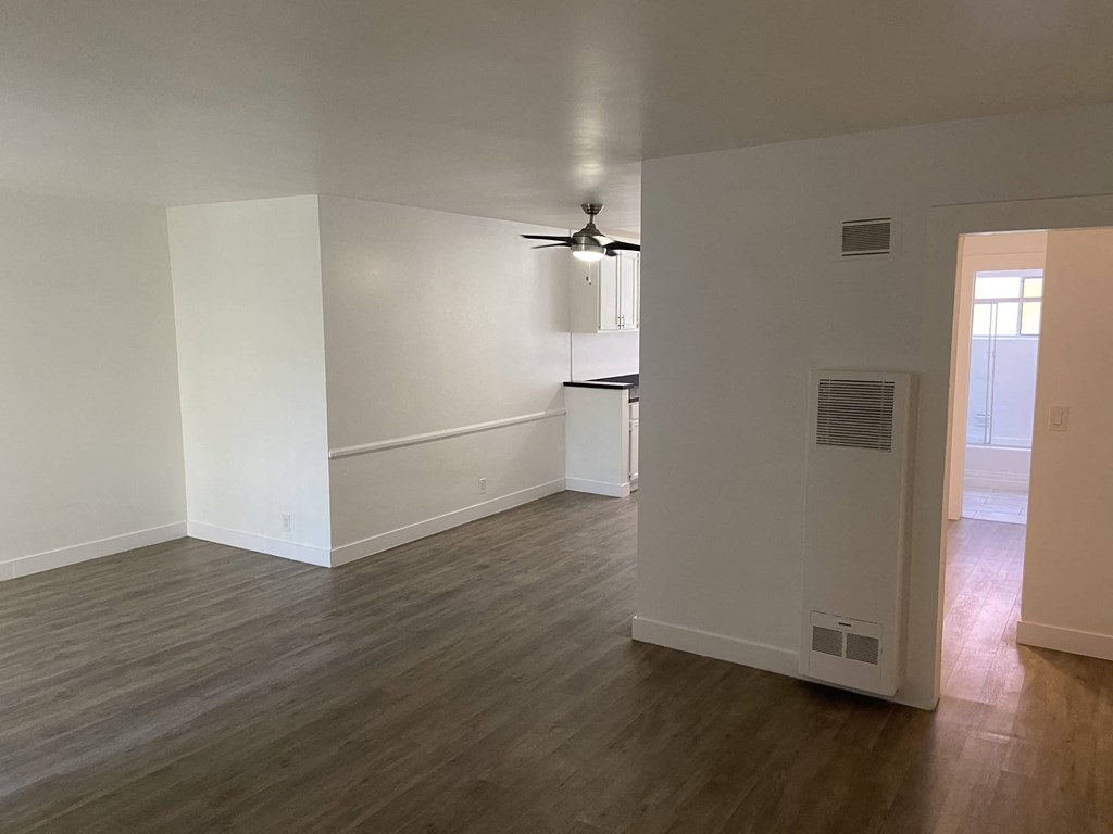 a living room and kitchen with white walls and wood floors