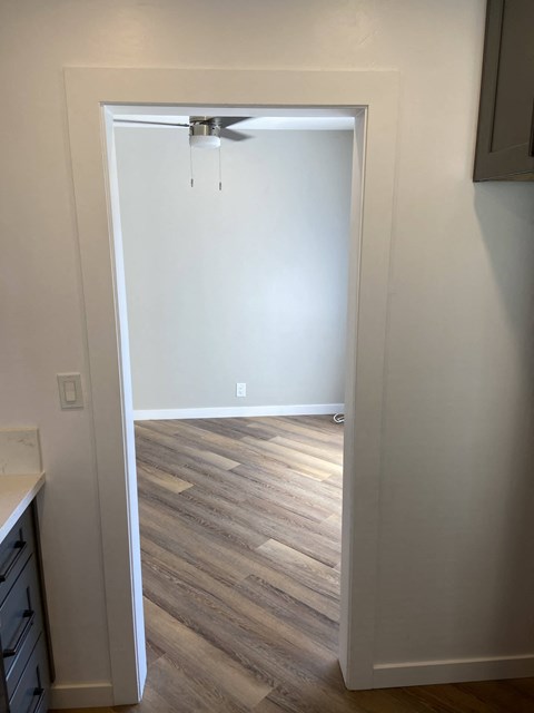 a doorway into a room with wood floors and a ceiling fan