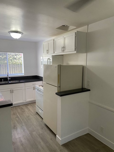 an empty kitchen with white cabinets and a refrigerator