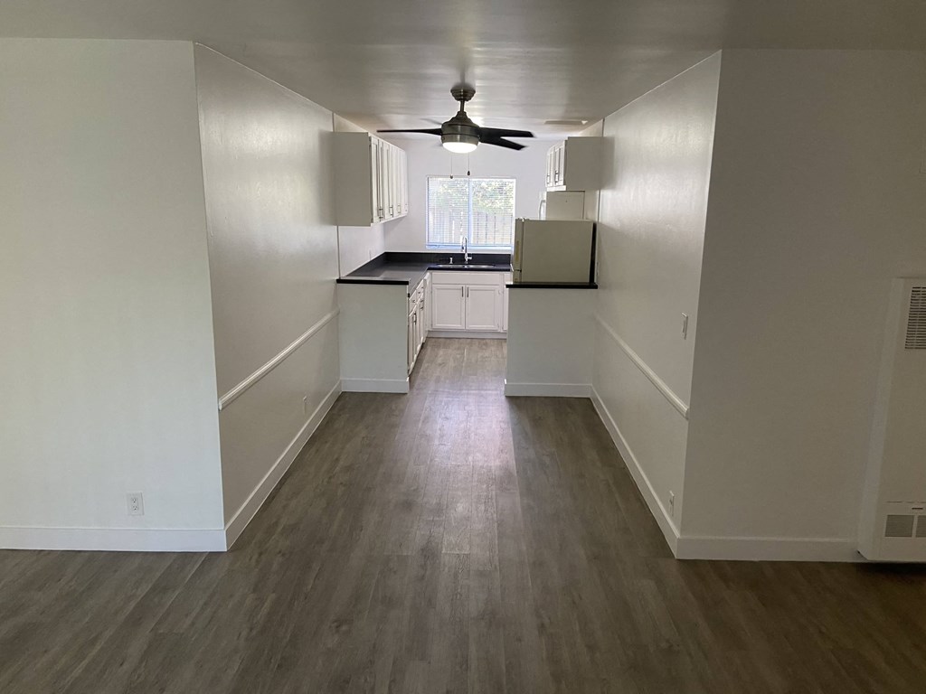 an empty kitchen with white walls and a ceiling fan