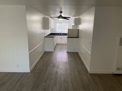 an empty kitchen with white walls and a ceiling fan