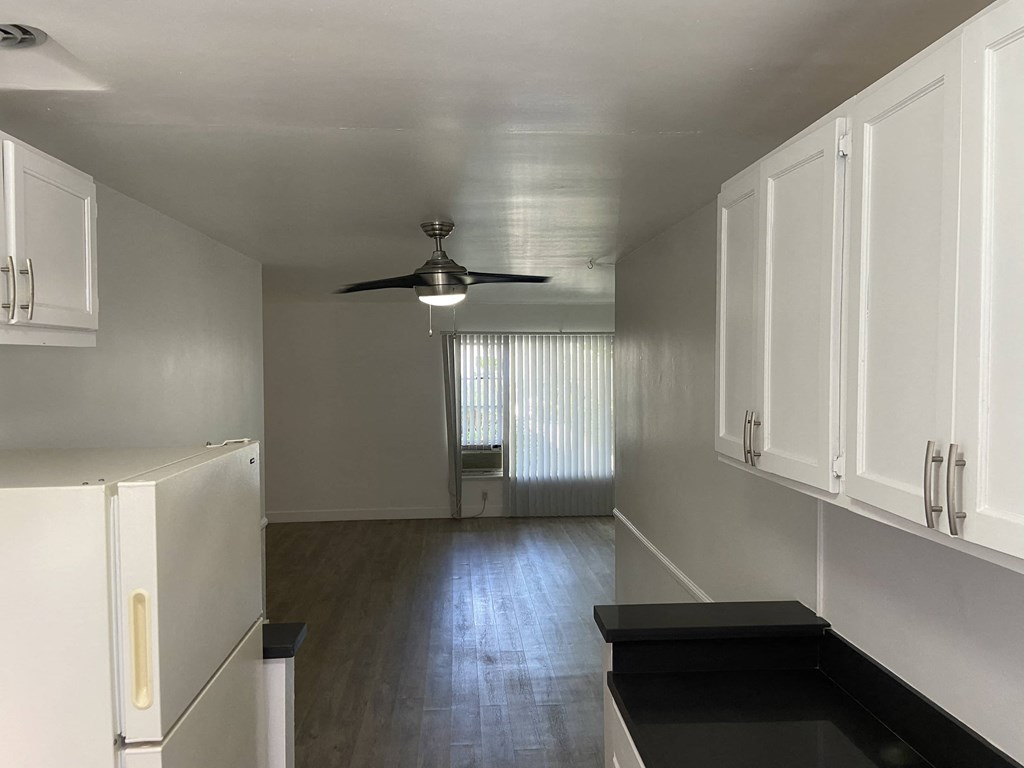 an empty kitchen with white cabinets and a ceiling fan