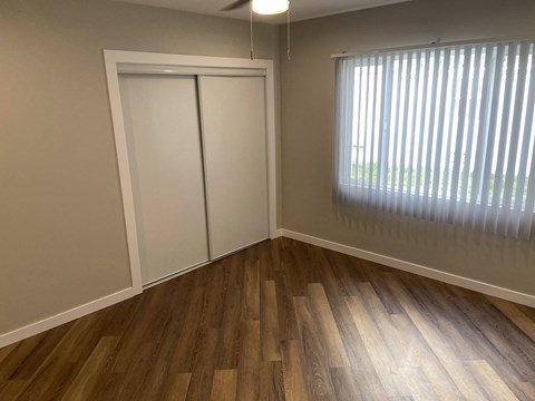 a bedroom with wood floors and a window and a closet