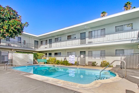 A pool in front of a white building with balconies.