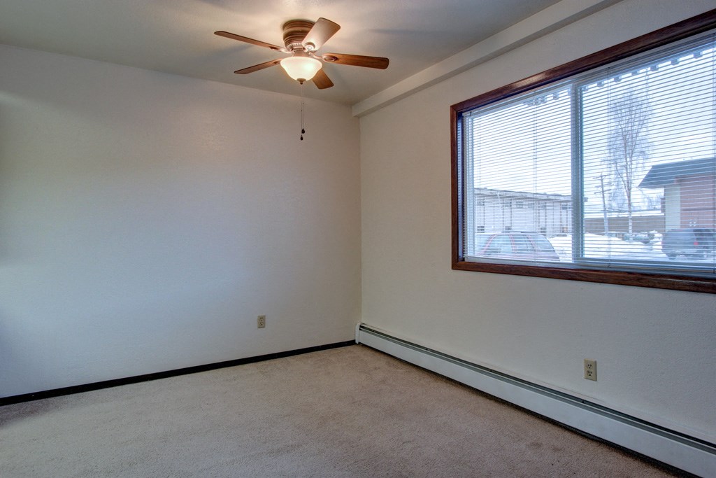 the living room of a home with a large window and a ceiling fan