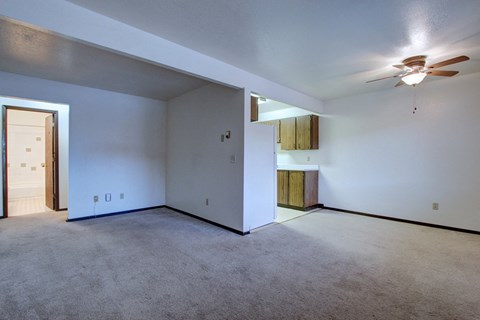the living room of an empty house with a ceiling fan