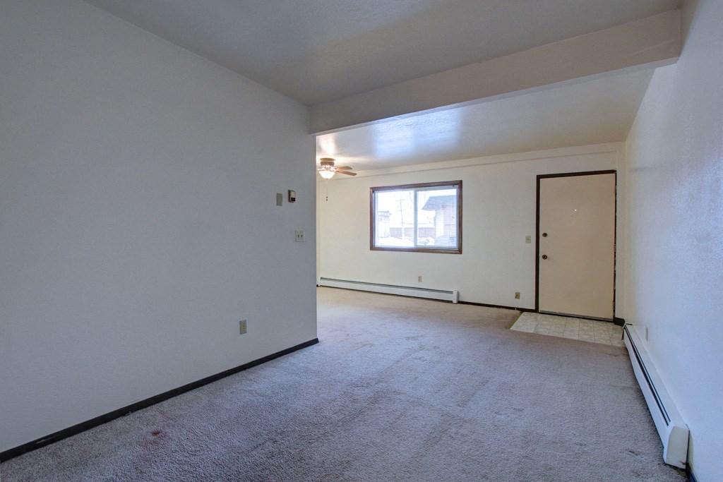 an empty living room with white walls and a window