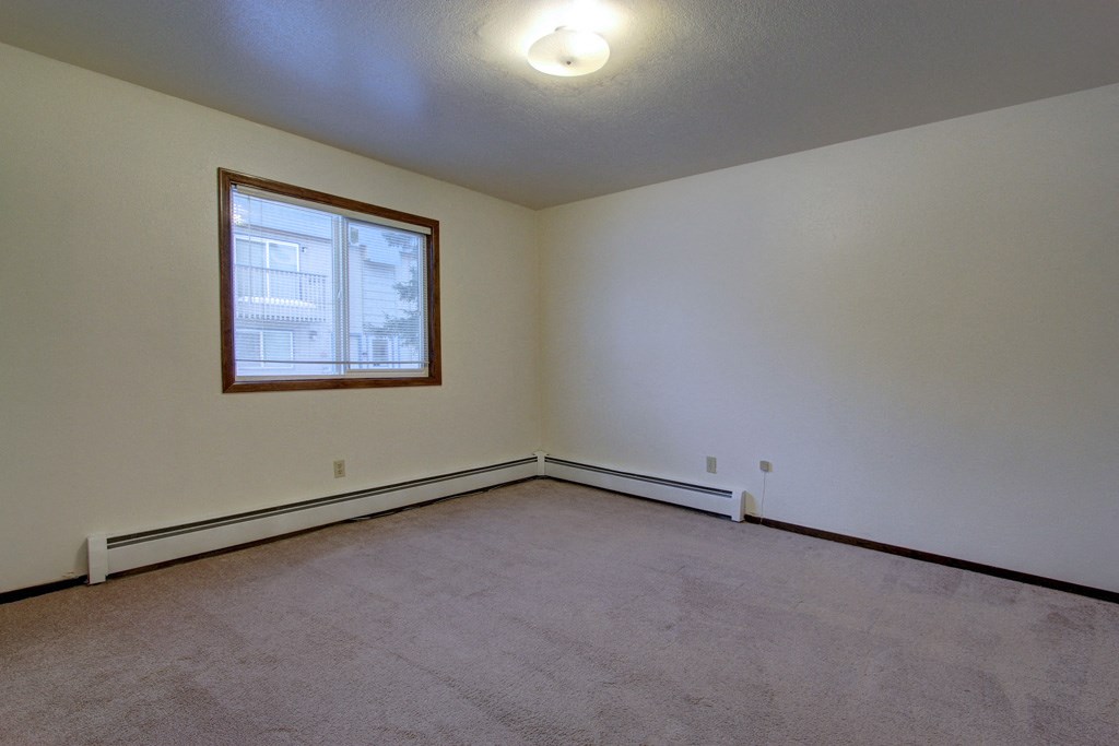 the living room of a home with white walls and a window