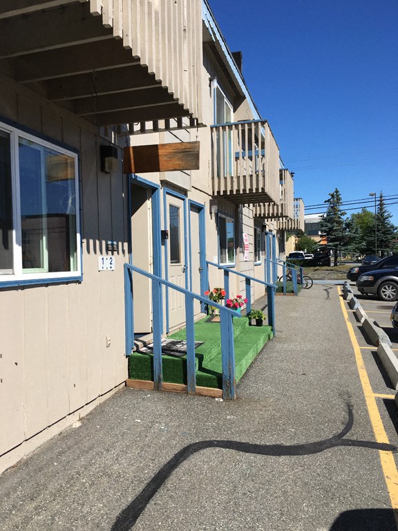 the outside of a building with a blue railing and a green rug on the sidewalk