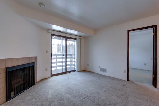 a living room with a fireplace and a door to a balcony