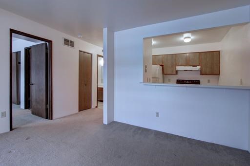an empty room with a kitchen and a living room