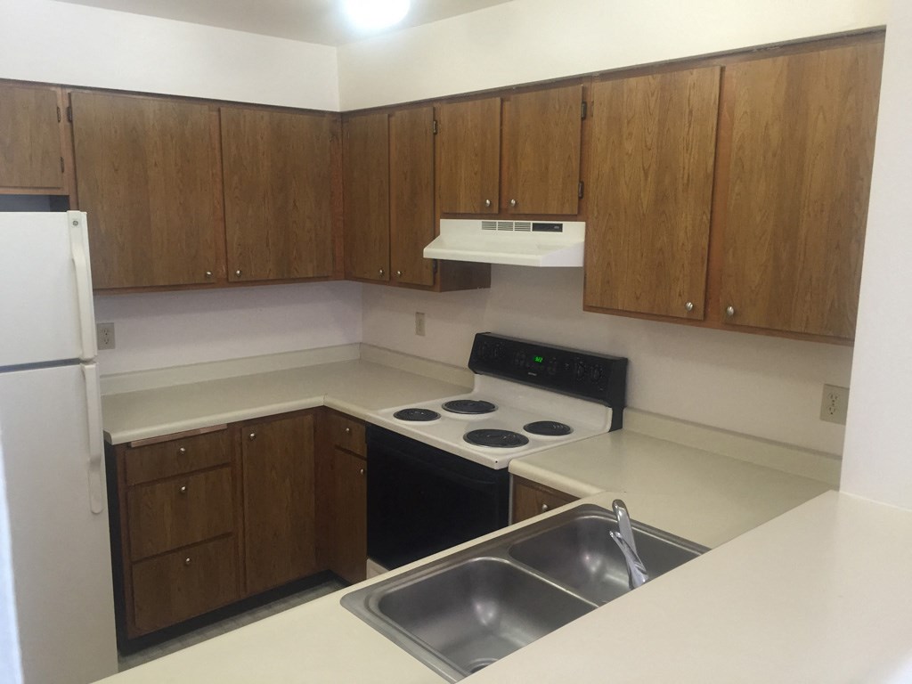 an empty kitchen with wooden cabinets and a sink