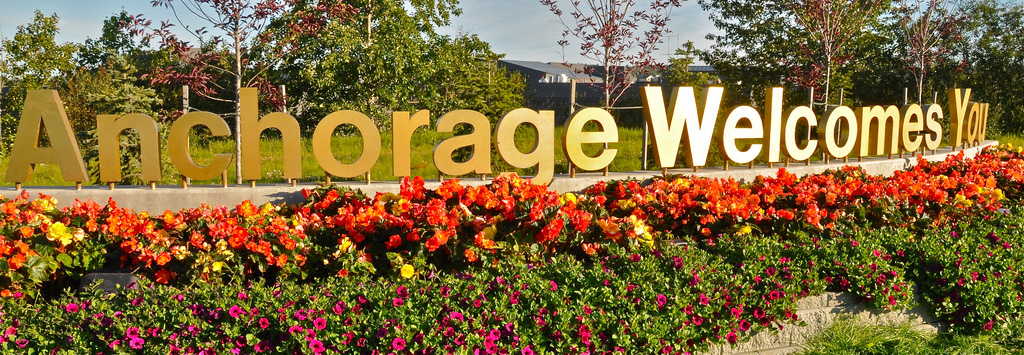 the sign for anchoorage welcome sign with flowers in front of it