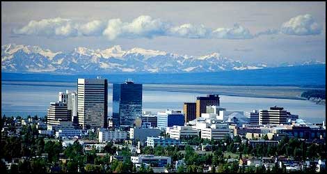 a city skyline with a lake and mountains in the background