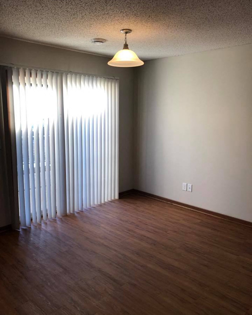 an empty living room with a wood floor and a window
