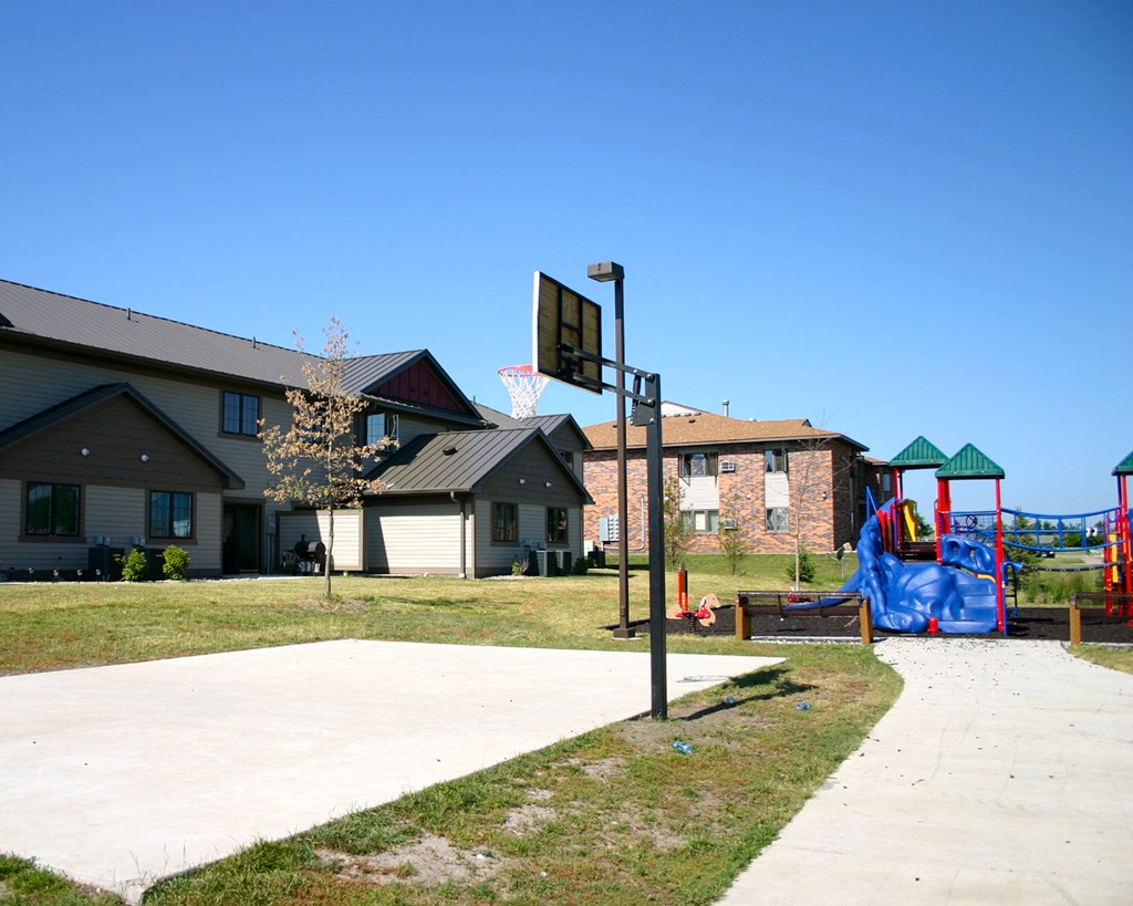 a playground in front of a house with a basketball hoop