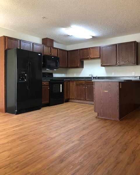 a large kitchen with wooden floors and black appliances