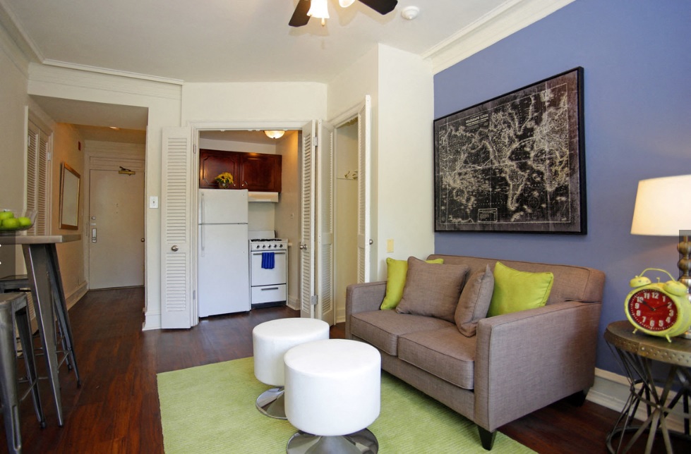 a living room with a couch and chairs and a kitchen