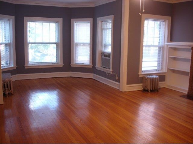an empty living room with a wood floor and windows