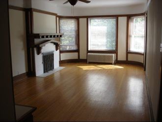an empty living room with a fireplace and wood floors