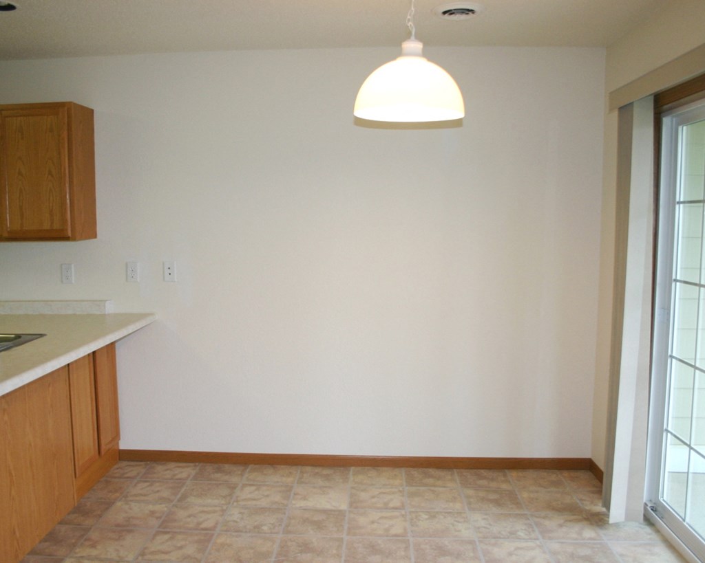 an empty kitchen with a white wall and a ceiling light