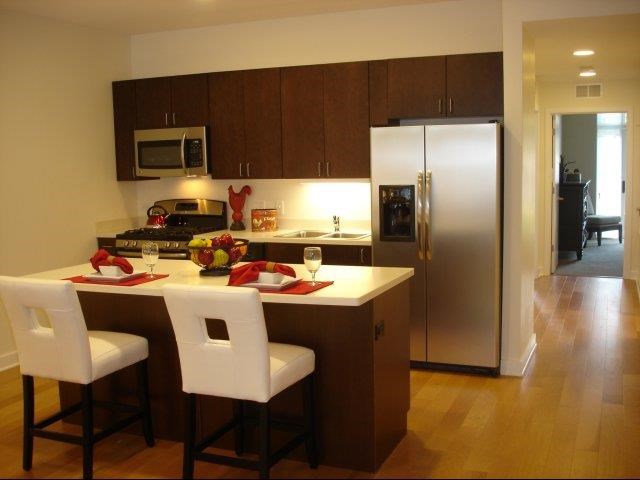 a kitchen with a counter and two white chairs