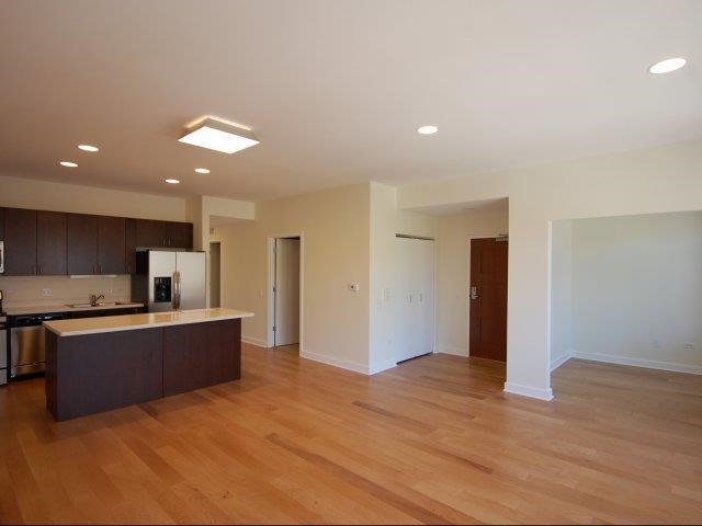 an empty living room and kitchen with wood floors