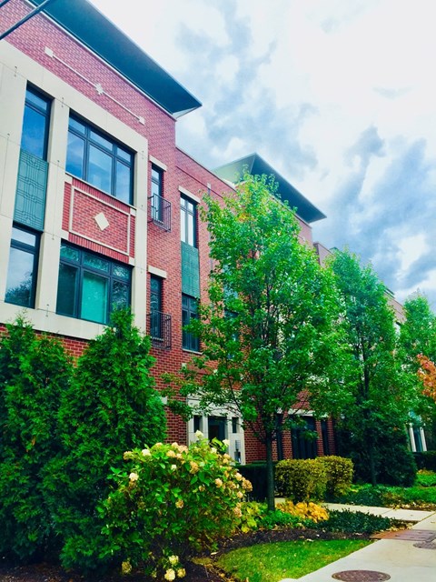 a red brick building with trees and bushes in front of it