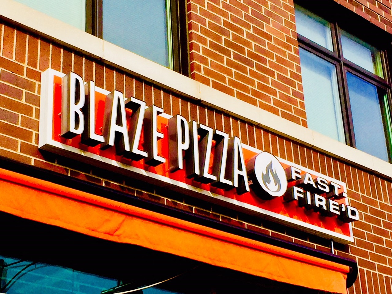 a sign for a pizza store on the side of a brick building