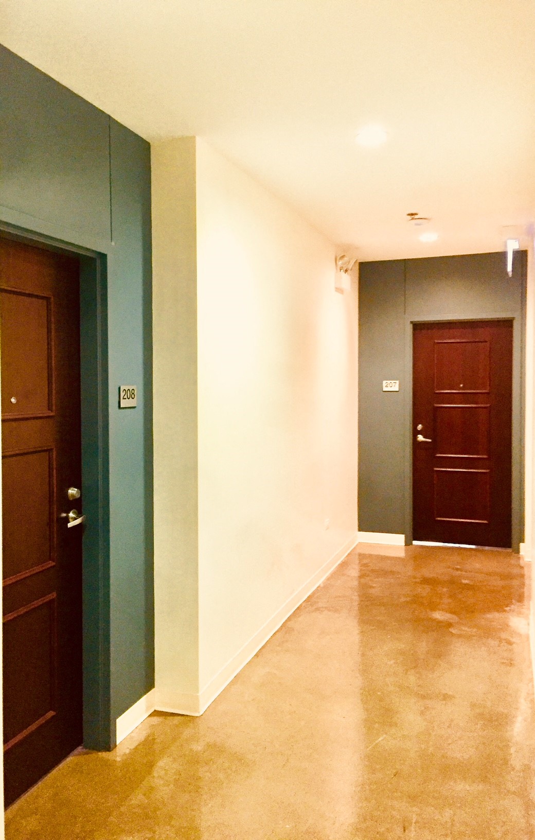 a hallway with two doors and a white wall and a tile floor