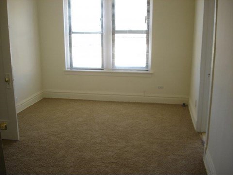 an empty room with a window and a carpet