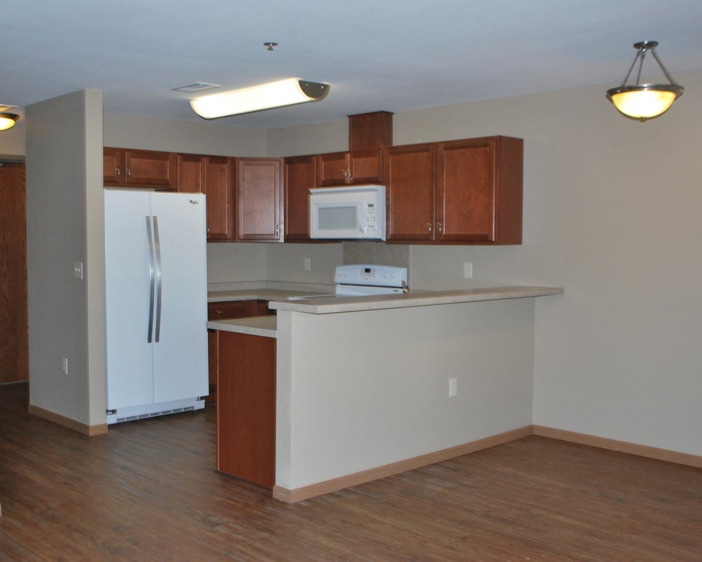 an empty kitchen with wooden cabinets and a white refrigerator