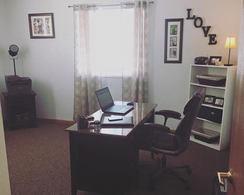a desk with a laptop and a chair in a room