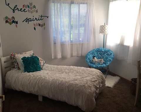 a small bedroom with a bed and a chair