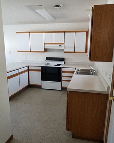 an empty kitchen with white cabinets and a black stove