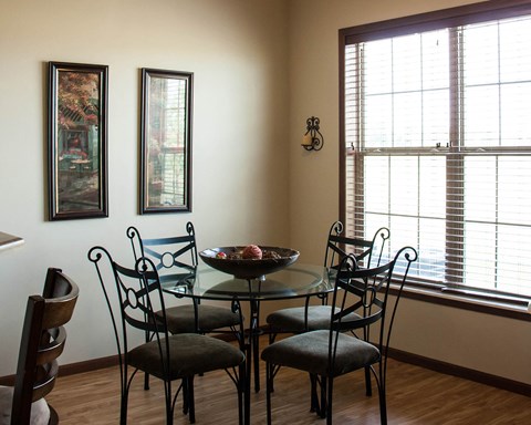 a dining room with a glass table and chairs and two windows