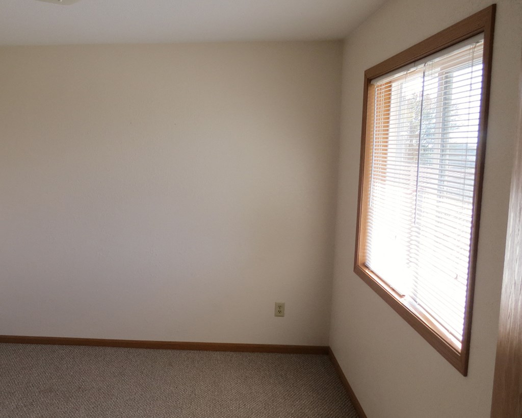 a bedroom with a large window and a carpeted floor