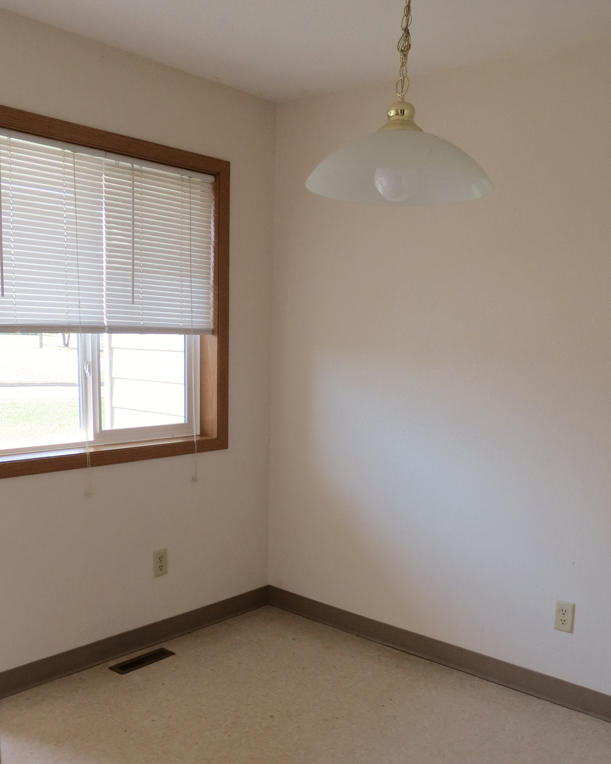 an empty room with a window and a lamp