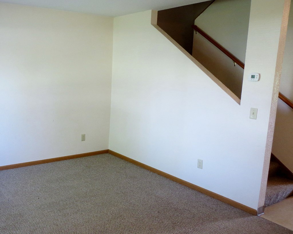 an empty room with white walls and a staircase