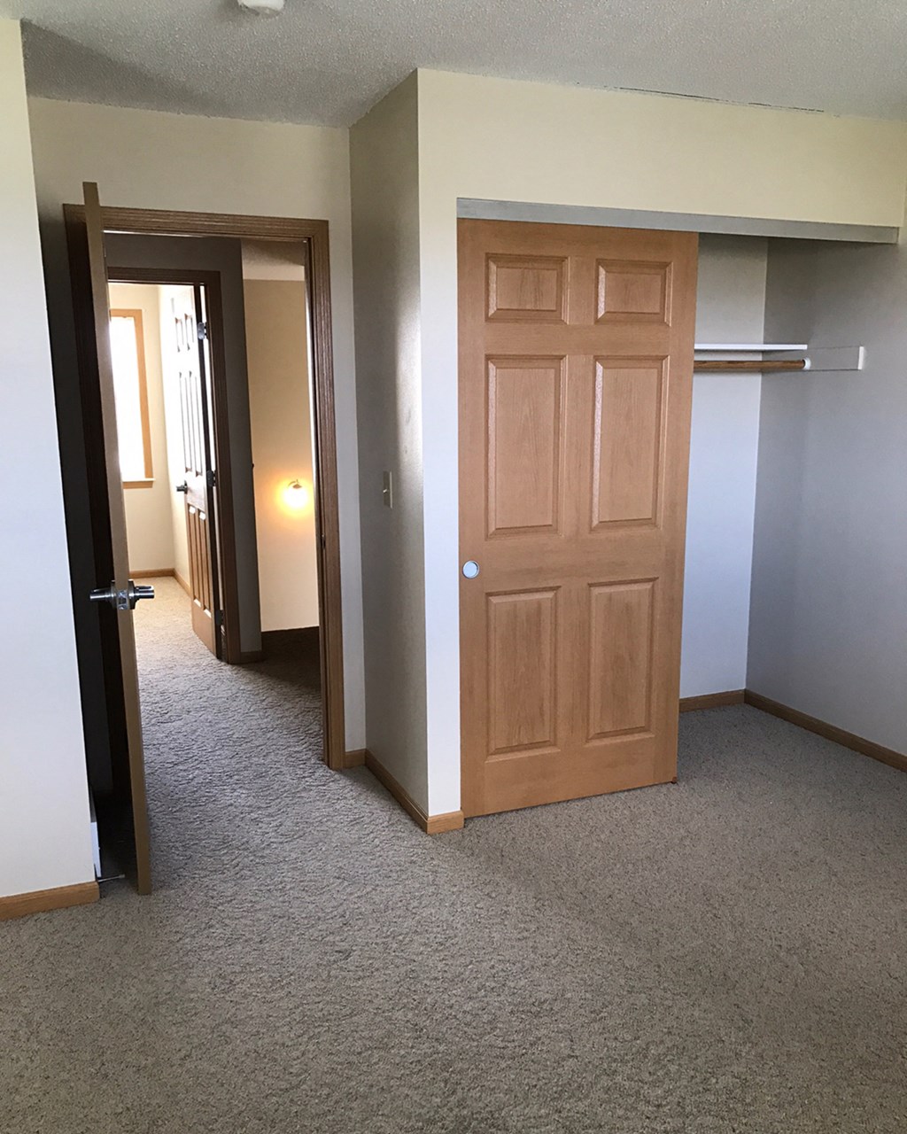 a bedroom door and a hallway with a closet and a mirror