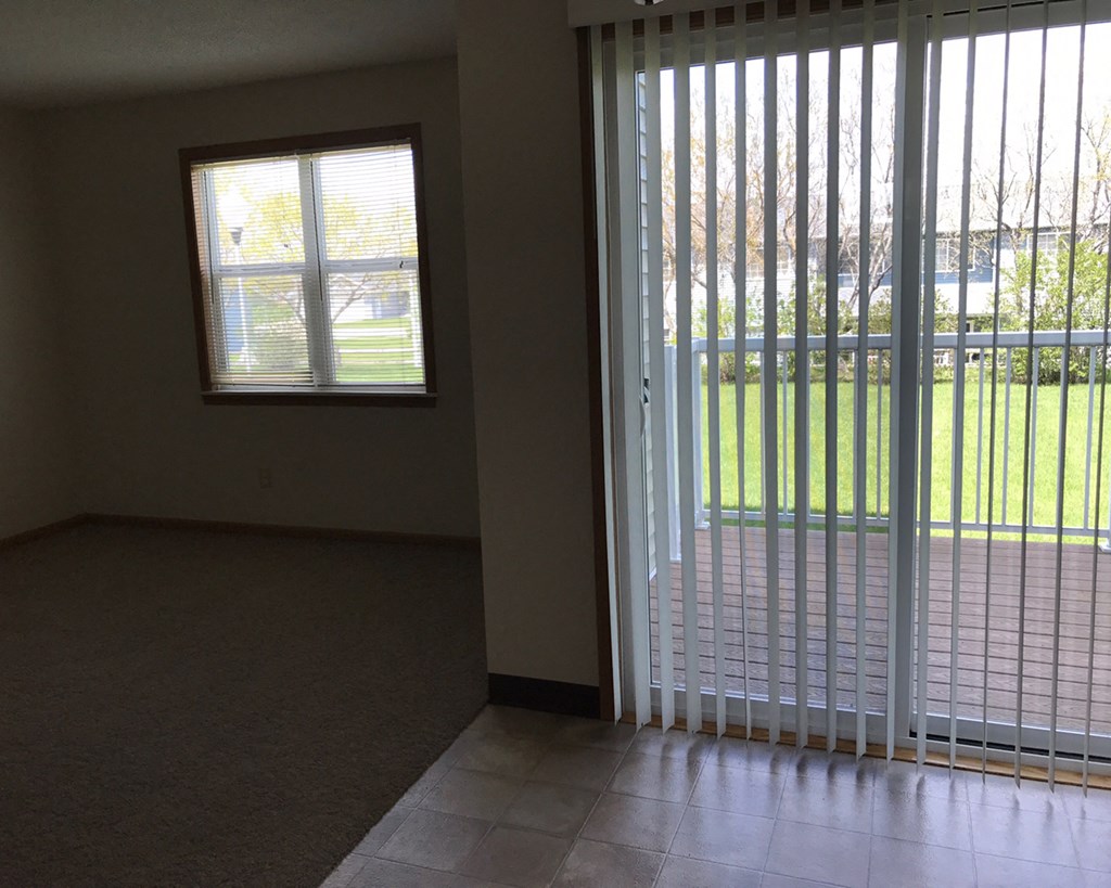 an empty living room with sliding glass doors to a yard