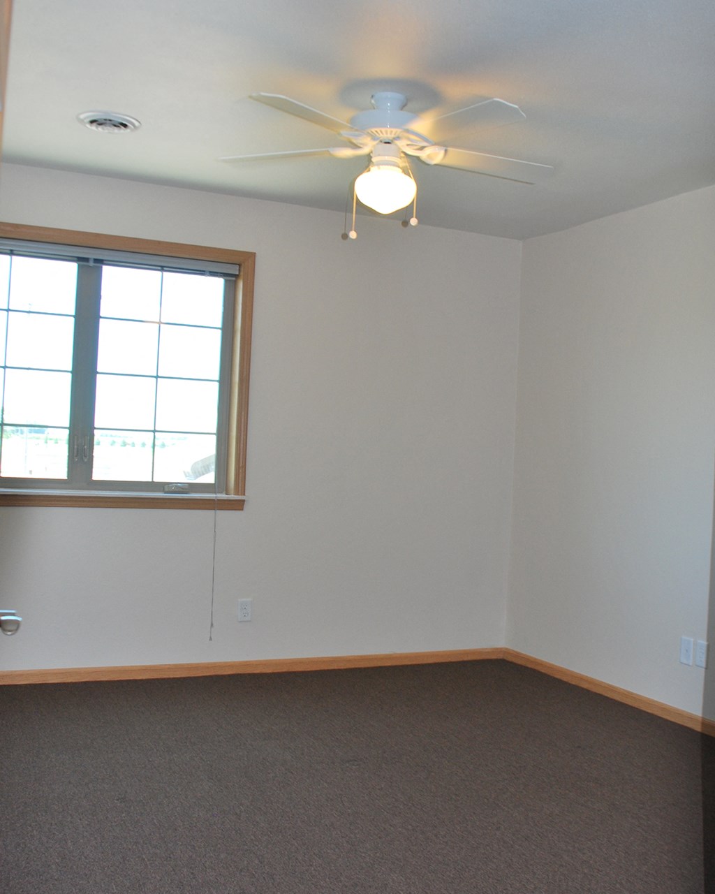 an empty room with a ceiling fan and a window