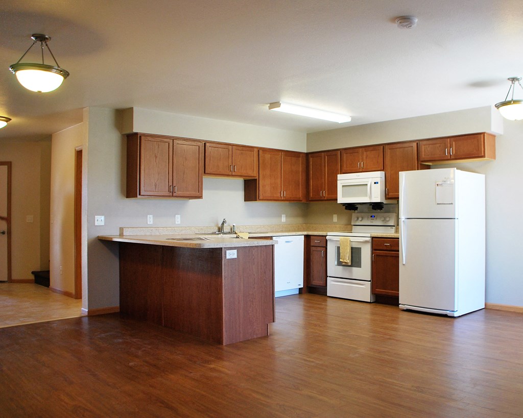 an empty kitchen with white appliances and wooden cabinets