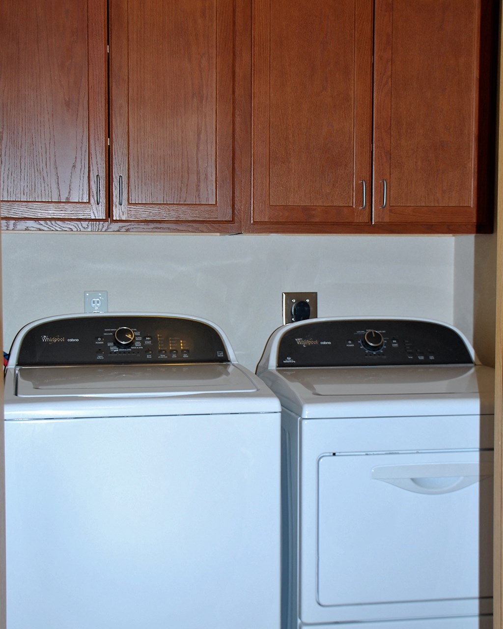 a washer and dryer in a laundry room with wooden cabinets