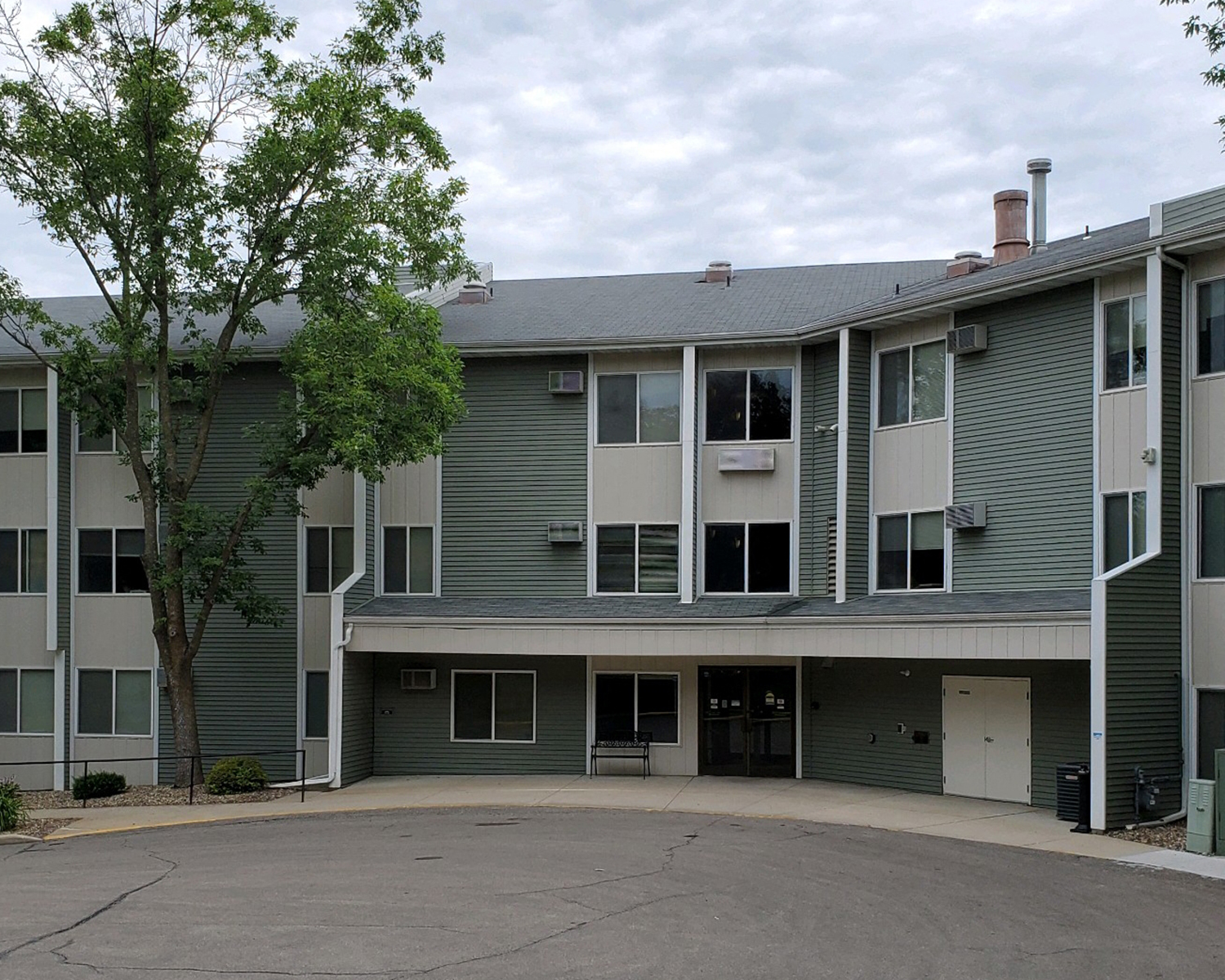 an apartment building with a driveway and a tree