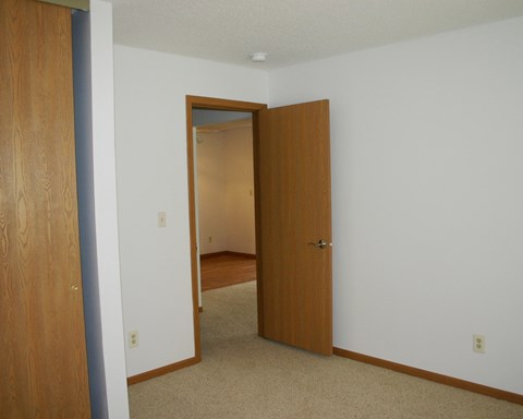 a bedroom with a door to a hallway and a closet