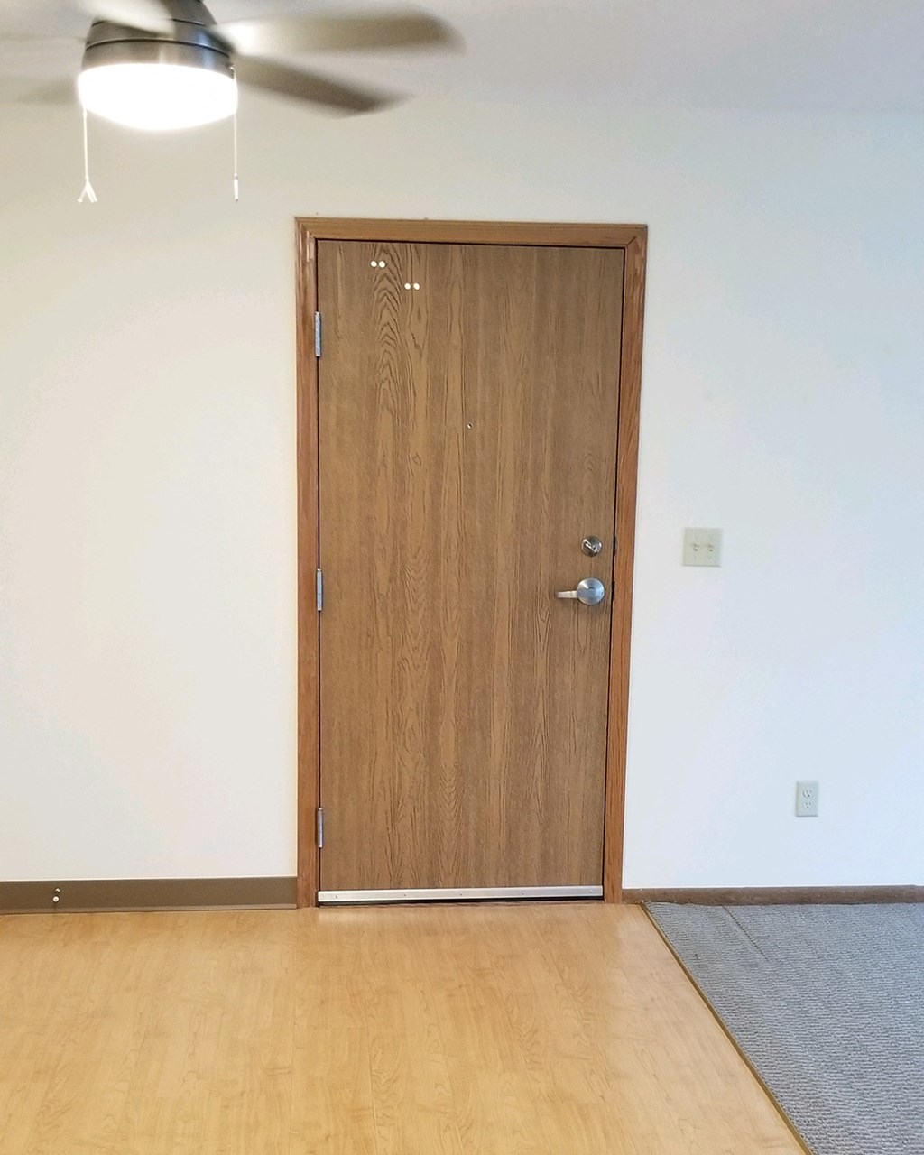 a wooden door in a room with wood flooring and a ceiling fan